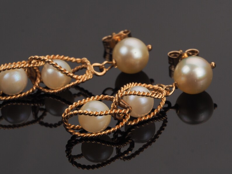 May include: A pair of gold earrings with pearl drops. Each earring features a twisted gold wire design with three pearls.