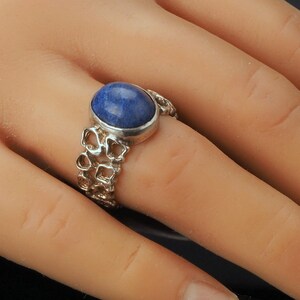 May include: A silver ring with a blue gemstone set in a delicate, intricate design.