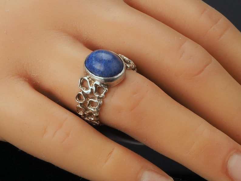 May include: A silver ring with a blue gemstone set in a delicate, intricate design.