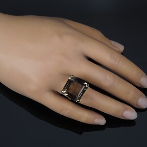 May include: A gold ring with a large, square-shaped smoky quartz gemstone.
