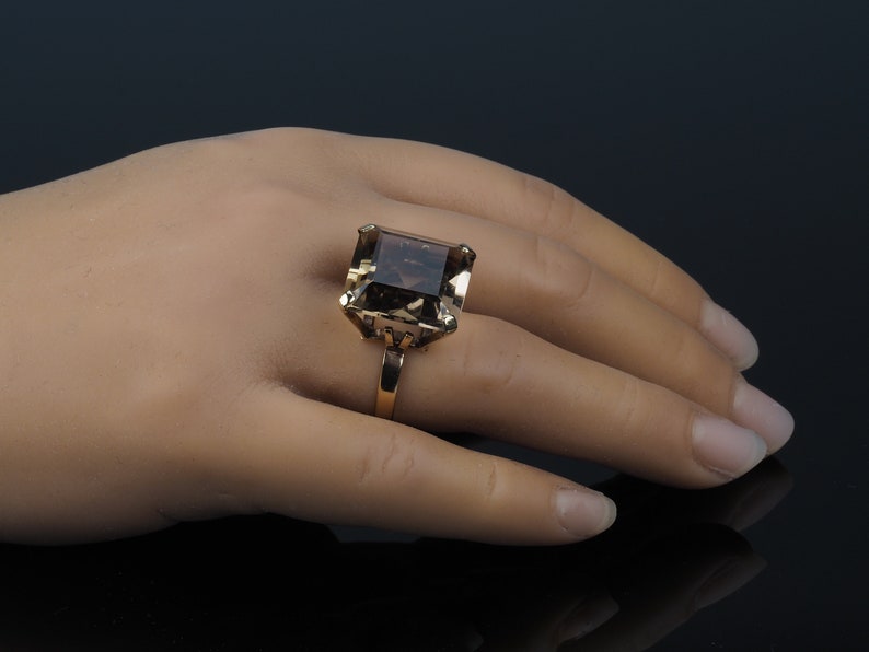 May include: A gold ring with a large, square-shaped, smoky quartz gemstone.
