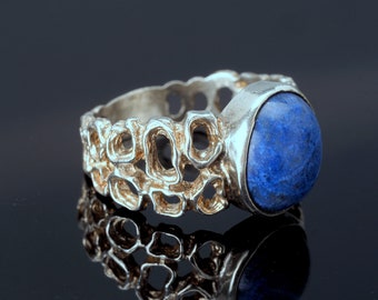 Può includere: Un anello d'argento con una pietra preziosa blu incastonata in una fascia testurizzata.