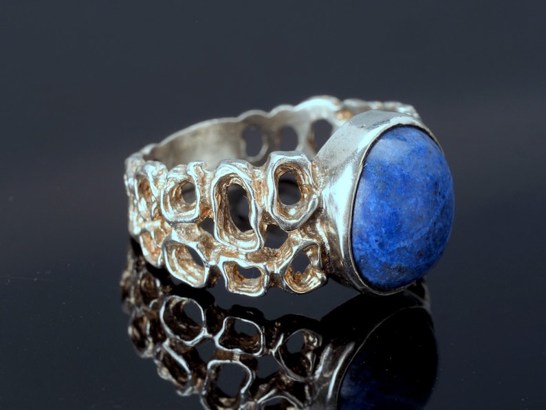 May include: A silver ring with a blue gemstone set in a textured band.