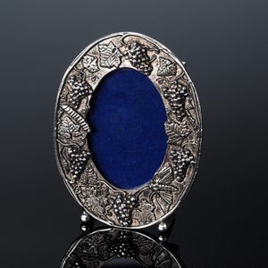 Silver tone very decorative miniature photo frame in oval form. Decorated with Art nouveau decoration. 
Has text around the sides of the frame.