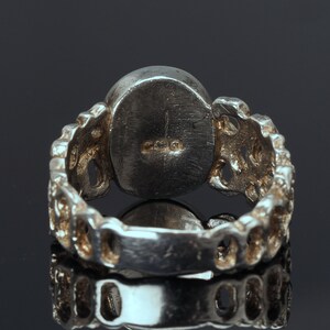 May include: Silver ring with a round, textured band and a smooth, round stone. The ring is marked with the number "925" on the inside of the band.