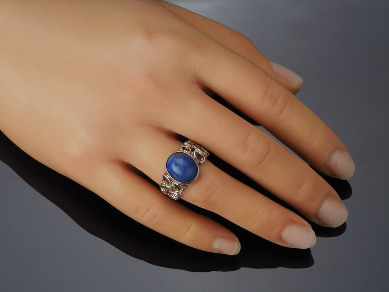 May include: A silver ring with a blue oval gemstone set in a chain-link band.