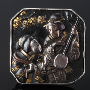 Pu&ograve; includere: Un netsuke giapponese in argento e oro del periodo Edo che raffigura due donne, una delle quali suona uno shamisen, uno strumento musicale a tre corde. Il netsuke &egrave; finemente intagliato con dettagli dei loro vestiti e dello strumento.