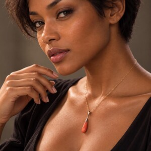 Pu&ograve; includere: Una collana a catena in oro con un ciondolo in corallo liscio a forma di goccia. Il ciondolo &egrave; sospeso a una contromaglia in oro lucido, creando un gioiello semplice ed elegante che poggia sulla clavicola.