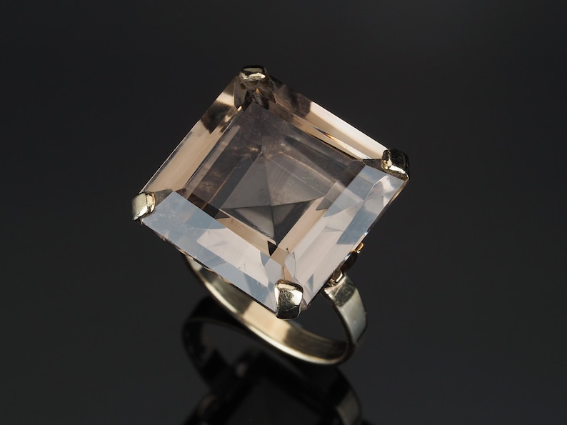 May include: A gold ring with a large, square-shaped, smoky quartz gemstone.