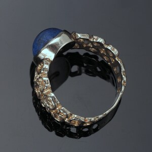 May include: A silver ring with a blue gemstone set in a textured band.