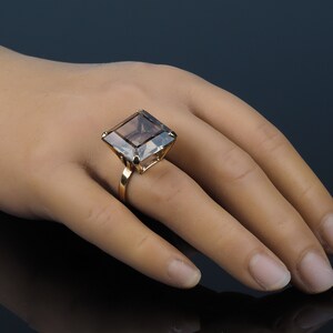 May include: A gold ring with a large, square, smoky quartz gemstone.