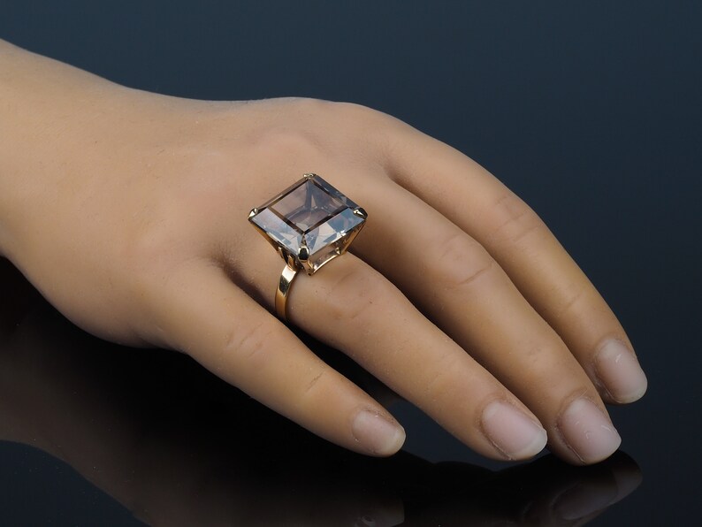 May include: A gold ring with a large, square, smoky quartz gemstone.