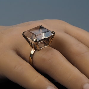 Huge modernist minimalist retro gemstone ring with a very high mount. The 9k gold ring has a large Caringorm quartz gemstone set into a high gold pronged open mount. The gold band is flat and plain. The square Cairngorm stone is cushion cut.
