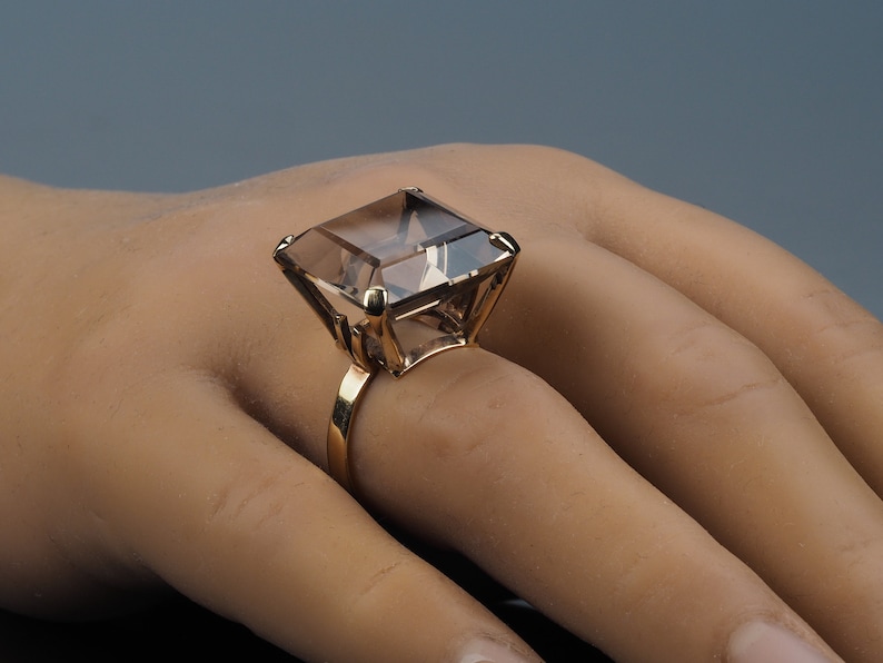 Huge modernist minimalist retro gemstone ring with a very high mount. The 9k gold ring has a large Caringorm quartz gemstone set into a high gold pronged open mount. The gold band is flat and plain. The square Cairngorm stone is cushion cut.