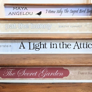 May include: A wooden staircase with four risers decorated as book spines. The titles include Maya Angelou's I Know Why The Caged Bird Sings, Pat the Bunny by Dorothy Kunhardt, A Light in the Attic by Silverstein, and The Secret Garden by Frances Hodgson Burnett.