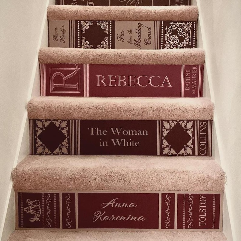 May include: A staircase with beige carpeted treads and risers decorated with book spine decals. The decals feature titles including Far from the Madding Crowd, Rebecca, The Woman in White, and Anna Karenina in maroon and white.