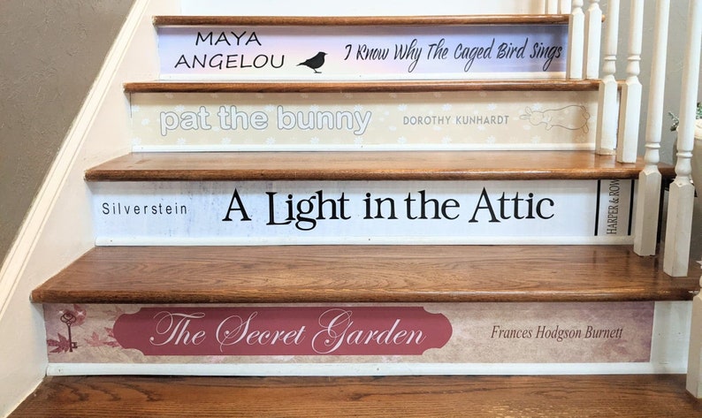 May include: A wooden staircase with four risers decorated as book spines. The titles include Maya Angelou's I Know Why The Caged Bird Sings, Pat the Bunny by Dorothy Kunhardt, A Light in the Attic by Silverstein, and The Secret Garden by Frances Hodgson Burnett.