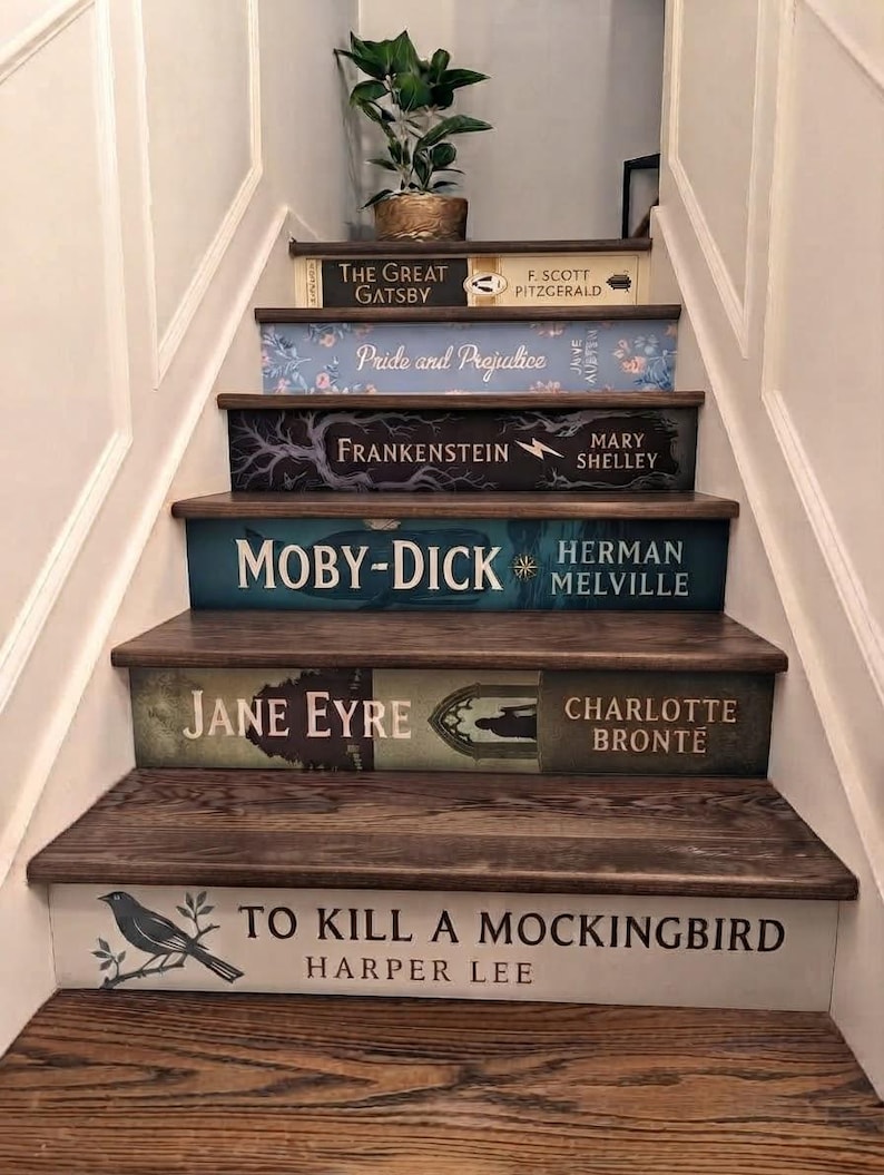 May include: A staircase with risers decorated to resemble book spines, featuring titles including The Great Gatsby, Pride and Prejudice, Frankenstein, Moby-Dick, Jane Eyre, and To Kill a Mockingbird, with a small potted plant on the top step.