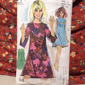 May include: Vintage Maudella dress pattern, size 12, featuring illustrations of dresses with floral and solid designs. The pattern includes bust 34 inches and hip 36 inches measurements. The package is set against a red floral fabric.