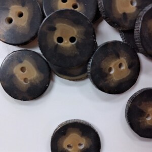 May include: A collection of brown and tan two-hole buttons with a mottled pattern. The buttons are round and have a raised edge.