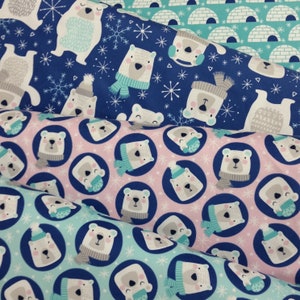 Puede incluir: Tres patrones de tela diferentes con osos polares que llevan gorros y bufandas de invierno. El primer patrón es azul con copos de nieve blancos, el segundo es rosa con copos de nieve blancos y el tercero es azul claro con copos de nieve blancos.