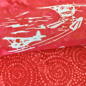 May include: Red fabric with a white airplane design. The fabric has a white polka dot pattern on the back side.