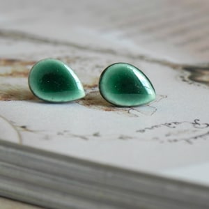 May include: A pair of teardrop-shaped earrings with a green enamel finish. The earrings are small and delicate.