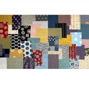 Puede incluir: Una colección de 40 cuadrados de tela con varios patrones de inspiración japonesa en tonos de azul, rojo, dorado y blanco. Los cuadrados de tela están dispuestos en un patrón de cuadrícula.