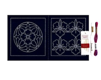 Puede incluir: Un panel de tela azul oscuro con patrones geométricos y florales cosidos en blanco, acompañado de un pequeño paquete etiquetado Orimono Imports Sashiko Needle, un hilo de bordar blanco y un hilo de bordar rosa y morado jaspeado.