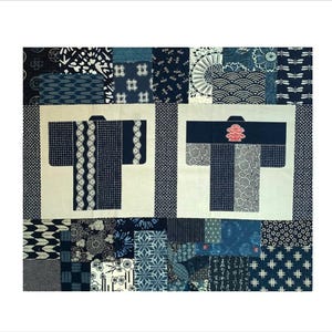 May include: A textile quilt featuring a patchwork of various indigo blue and white Japanese-inspired patterns. Two central cream-colored squares each display a stylized kimono graphic, one with vertical stripes and the other with a small red emblem.