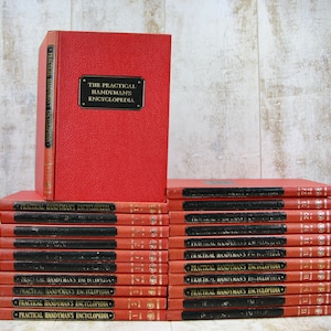 May include: A set of 22 red hardcover books titled "The Practical Handyman's Encyclopedia". The books are stacked on top of each other and have black titles on the spines.