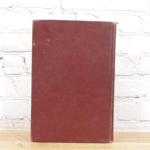 Pu&ograve; includere: Un libro rilegato in tela color bordeaux con una copertina liscia.