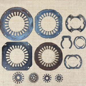 May include: An assortment of aged metal components, including circular and square shapes with intricate cut-out patterns. The pieces vary in color from blue to brown, with signs of rust and wear. The arrangement suggests industrial or mechanical parts.