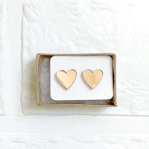 May include: A pair of gold heart-shaped earrings in a small cardboard box.
