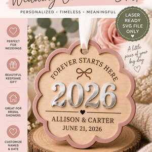 Op de afbeelding: Een geschulpt houten ornament met de gegraveerde tekst FOREVER STARTS HERE, het jaartal 2026 in verhoogde zilveren letters, en de namen ALLISON & CARTER met de datum JUNE 21, 2026. Een wit lint is aan de bovenkant bevestigd om op te hangen.