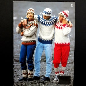 Puede incluir: Tres personas con suéteres y gorros de punto a juego. Los suéteres presentan un patrón geométrico blanco, marrón y rojo. La persona de la izquierda lleva vaqueros azules y la de la derecha, pantalones rojos. La persona del centro lleva vaqueros azules.