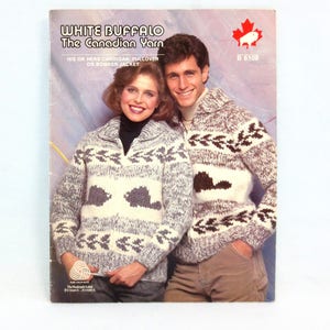 May include: A vintage book cover featuring a couple wearing matching knitted sweaters. The sweaters are white, gray, and brown with a geometric pattern. The cover text reads "WHITE BUFFALO The Canadian Yarn" and "HIS OR HERS CARDIGAN, PULLOVER OR BOMBER JACKET."