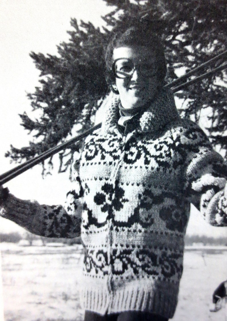 May include: A black and white photo of a person wearing a white and black patterned sweater. The person is holding a ski pole in their right hand and is standing in front of a tree.