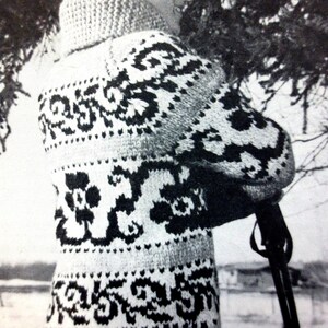 May include: A black and white patterned sweater with a high neck. The sweater has a floral design and is knitted.