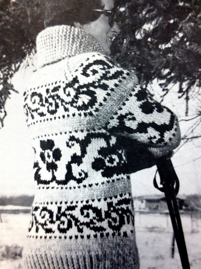 May include: A black and white patterned sweater with a high neck. The sweater has a floral design and is knitted.