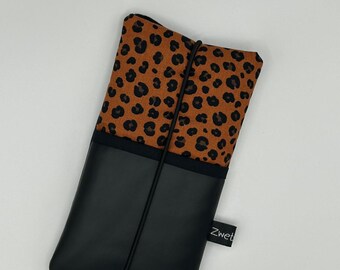 Peut inclure: Une coque de téléphone noire avec une doublure en tissu à imprimé léopard. La coque est dotée d'un élastique noir et d'une petite étiquette noire sur laquelle est inscrit le mot "Zwet".