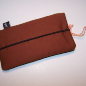 May include: A brown fabric pouch with a black elastic band closure. The pouch has a small black label with the word "SPOT" on it.