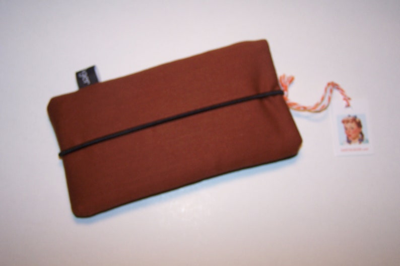May include: A brown fabric pouch with a black elastic band closure. The pouch has a small black label with the word "SPOT" on it.
