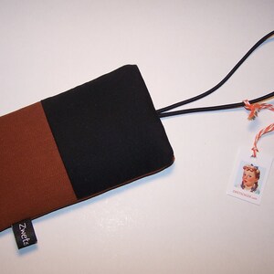 May include: A brown and black fabric phone case with a black elastic strap and a tag that says "sweetcicada.com".