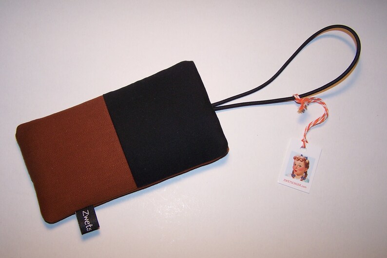 May include: A brown and black fabric phone case with a black elastic strap and a tag that says "sweetcicada.com".