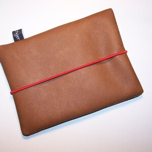 May include: A brown leather pouch with a red elastic band. The pouch has a small black label with the word "Finger" printed on it.
