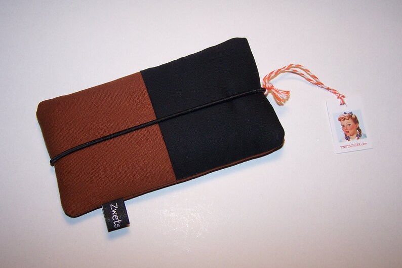 May include: A brown and black fabric phone case with a black elastic band and a black tag that says "Zwets".