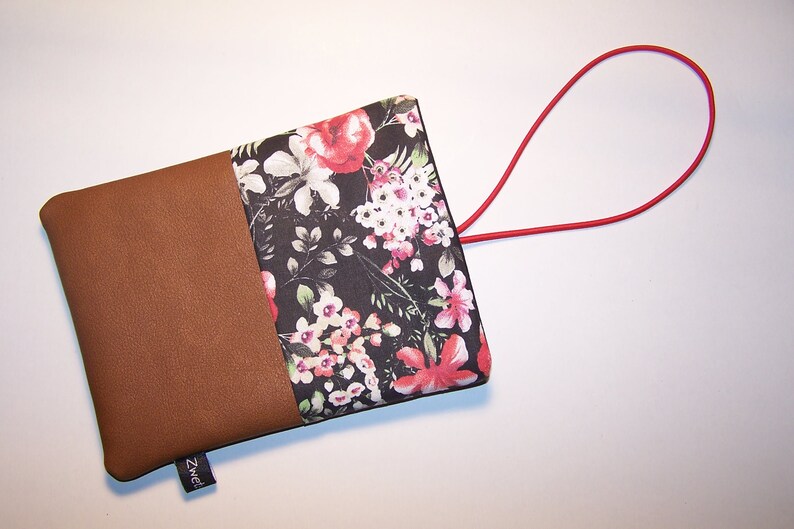 May include: A small brown and black floral pouch with a red elastic loop handle. The pouch has a brown fabric flap with the word "Zweed" printed on it.
