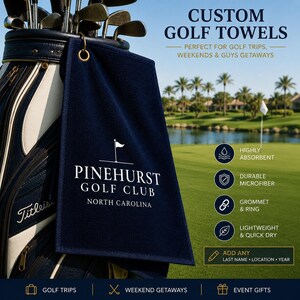 May include: A navy blue golf towel featuring the white text PINEHURST GOLF CLUB NORTH CAROLINA and a golf flag icon. The towel includes a gold-colored metal grommet and ring for attachment to a golf bag. The towel is displayed hanging from a golf bag.