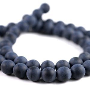 May include: A strand of dark blue matte round beads. The beads are strung together on a cord and are arranged in a circle.